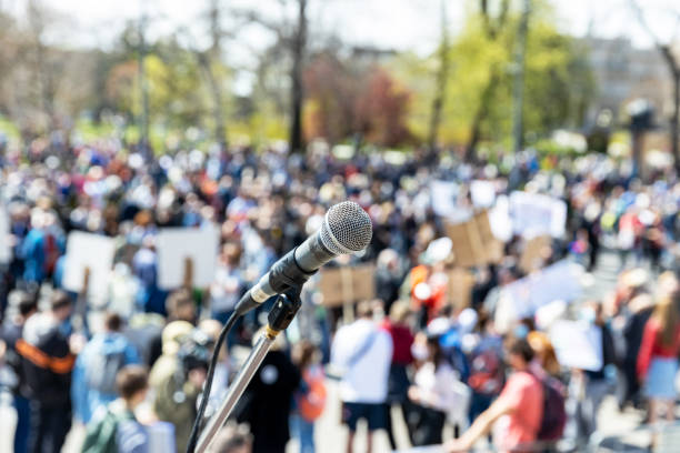 istock Protest or public demonstration, focus on microphone, blurred group of people in the background 1315851811