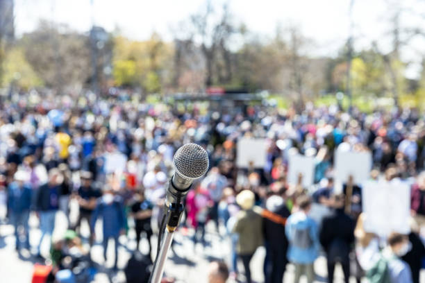 istock Blurred group of people at protest or public demonstration, focus on microphone 1315853029