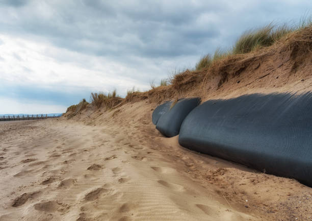 A rusty, corroded old metal waste pipe leading out into the sea at sunset, a long exposure photograph.