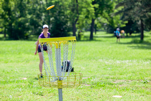 Young woman playing flying disc sport game in the nature