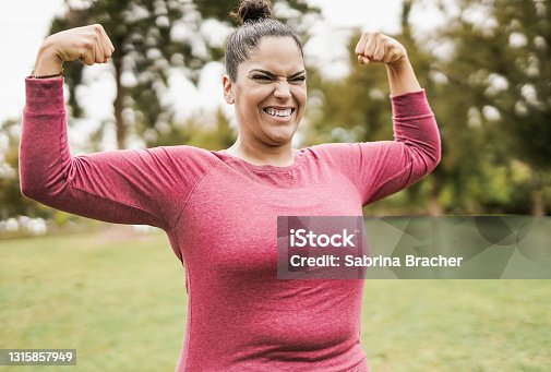 istock Young plus size body woman at city park posing showing biceps muscles 1315857949