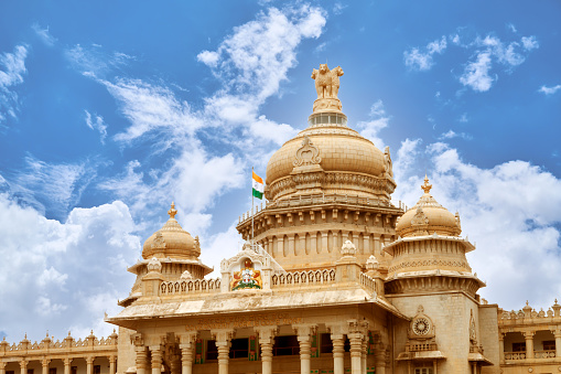 Close View of VIDHANA SOUDHA WITH INDIA FLAG FLYING HIGH( State Legislature Building) with a cloudy blue sky, at Bangalore, Karnataka, India