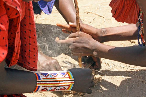 племя масаи делает огонь деревянной палкой в традиционной деревне. - национальный заповедник масаи стоковые фото и изображения