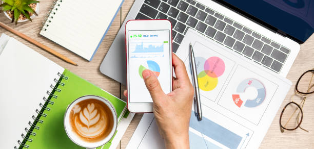 istock Man's hand using smartphone on wooden table with laptop, notebook and coffee 1315864096