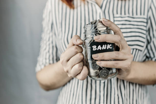 istock Glass bottle with coins in women's hands. 1315871438