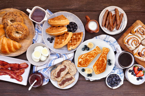 Fathers Day breakfast table scene. Top view on a dark wood background. Fathers Day breakfast table scene. Top view on a dark wood background. Tie pancakes, mustache toast and a selection of dad themed food. brunch stock pictures, royalty-free photos & images