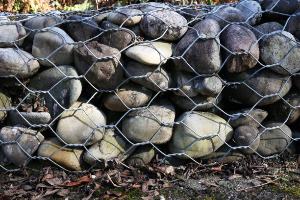 金属メッシュで保持された丸い石の壁 - gabion wall ストックフォトと画像