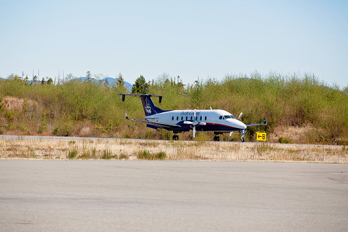 Bella Bella, Canada - April 24, 2021. A small passenger aircraft operated by Pacific Coastal Airlines, a regional airline within BC, arrives in the remote coastal community of Bella Bella.