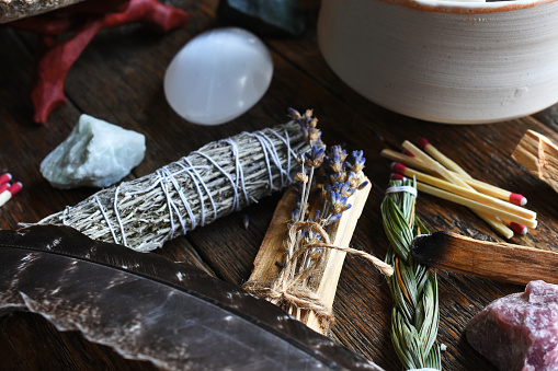 A close up image of several different types of healing incense and healing crystals on a dark wooden table.