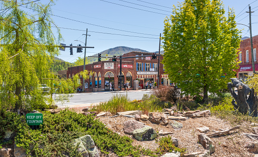 Black Mountain, NC, USA-1 May 2021: View of the Town Hardware corner from city park, showing foliage and rock garden.  People.  Sunny, spring day.