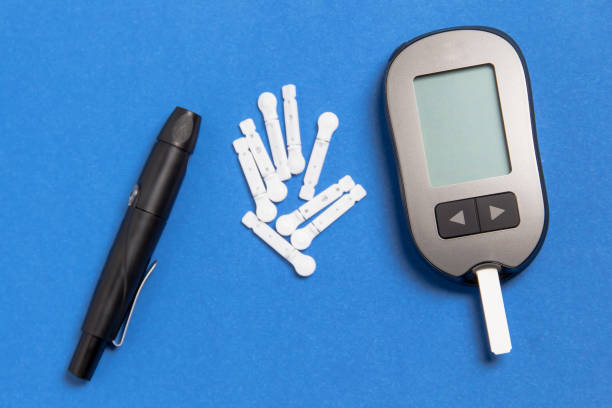 glaucometer with a needle on a blue background. measurement of blood glucose. - glaucometer imagens e fotografias de stock