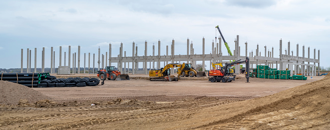 Berlin, Brandenburg, Germany - April 25, 2021: Amazon Germany builds a new Logistic Center next to Berlin Brandenburg. Construction site with Concrete pillar heavy duty crane and construction machinery.