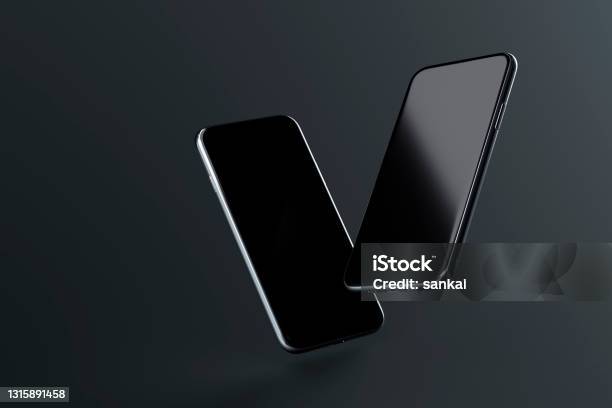 Two Smartphones With Blank Screen Soaring On Dark Background Stock Photo - Download Image Now