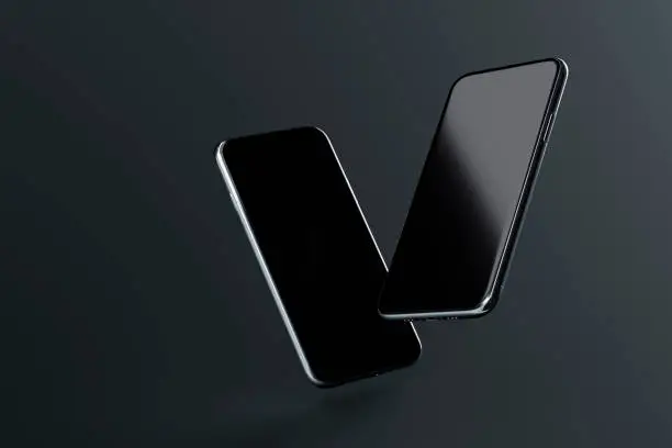 Photo of Two smartphones with blank screen soaring on dark background