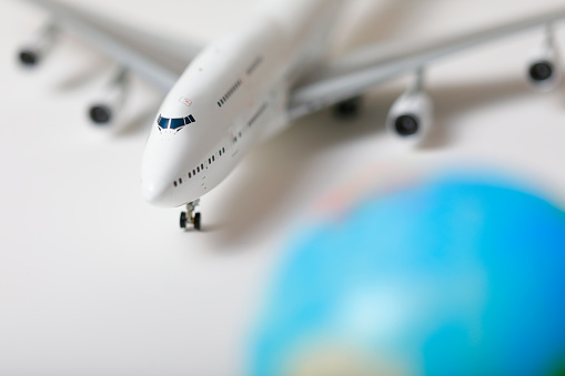 Unbranded white model of a passenger plane in scale 1/200 with a globe blurred in foreground