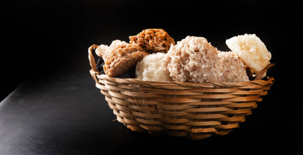 istock Cocada, Coconut candy from Brazil, white and brown cocadas in a straw basket on dark surface, black background, selective focus. 1315897851