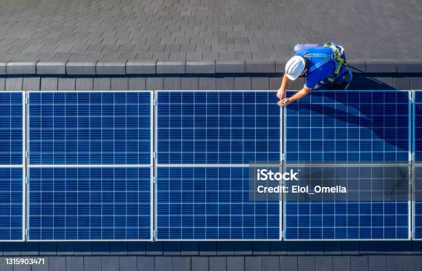 Solar Panel Installer Installing Solar Panels On Roof Of Modern House Stock Photo - Download Image Now