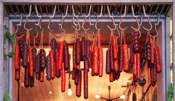 colgar salchichas ahumadas rojas en ganchos metálicos a la venta - garlic hanging string vegetable fotografías e imágenes de stock