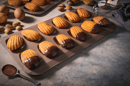 Madeleines Homemade with almond and melted chocolate on mold in a row freshly baked