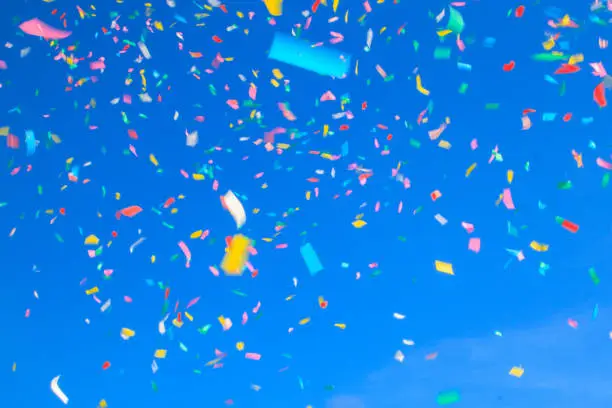 multicolored confetti on blue sky background