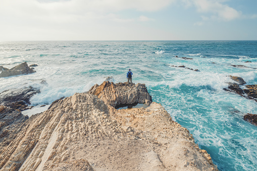 Dramatic ocean bluffs, summits with sweeping views, and silhouette of a man standing on the ege of a cliff. Montana de Oro State Park, Los Osos, California Central Coast