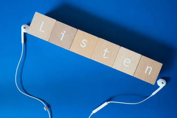 Listen; Six wooden blocks with Listen text of concept and earphones