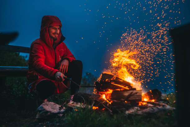 homem acende uma fogueira nas montanhas - bonfire people campfire men - fotografias e filmes do acervo