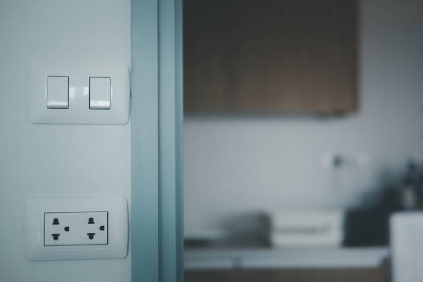 istock Group of white electrical outlets and a switch located on a gray wall in front of modern kitchen 1315939101
