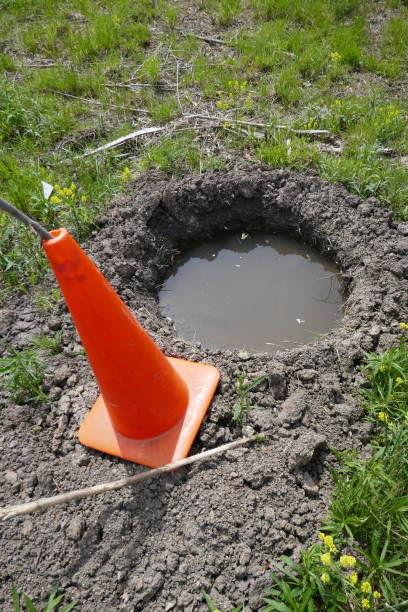 istock Orange traffic cone marking deep hole filled with water 1315946597