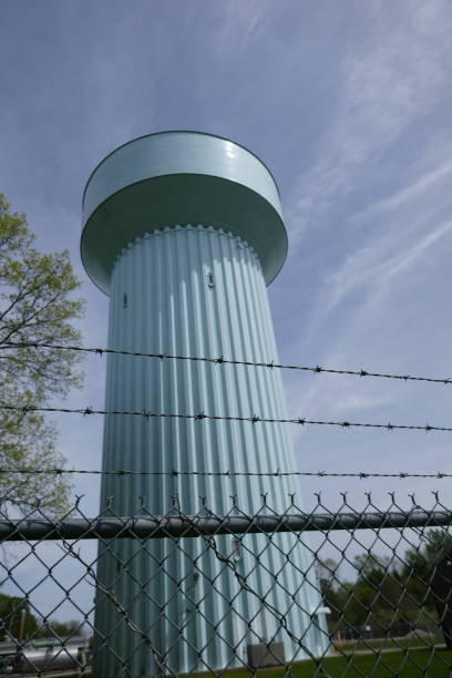 istock Large water tower against blue sky background and barbed wire in foreground 1315946638