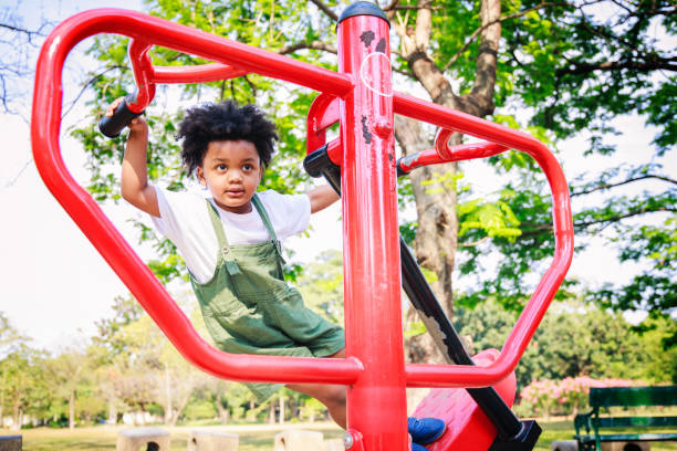 istock Cute African American little kid boy funny while playing on the Exercise machine in the daytime in the spring season 1315949168