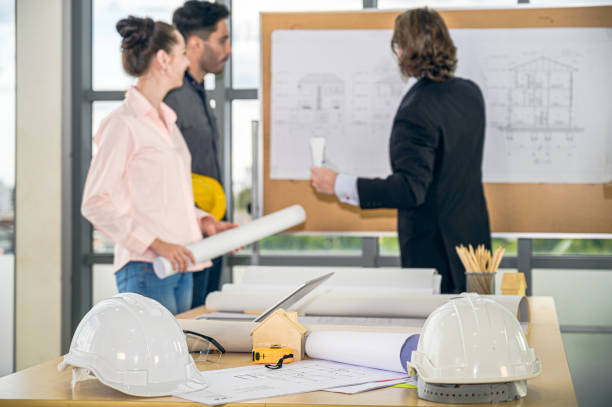 istock Close up engineer helmet, tools and many equipment with group of Caucasian engineer at the background. 1315949252
