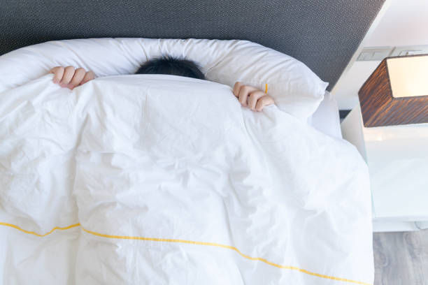istock Lazy boy covering his face with blanket while lying in bed at home, 1315952298