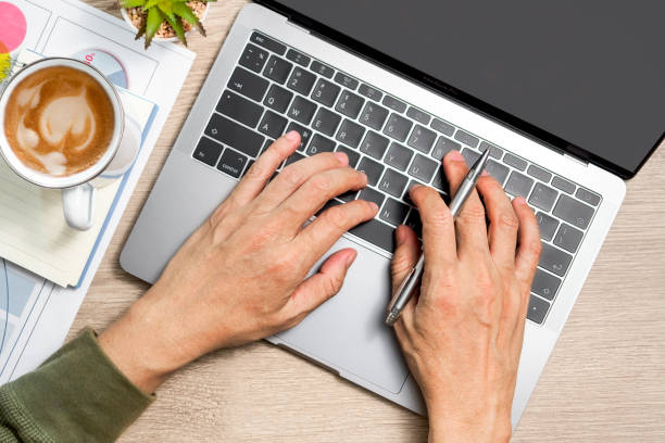 istock Man's hand typing laptop computer and notebook, coffee on wooden table 1315954014