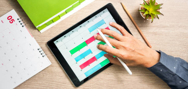 istock Man's hand using tablet computer to create business planning on calendar. Flat lay and top view of working space 1315954979