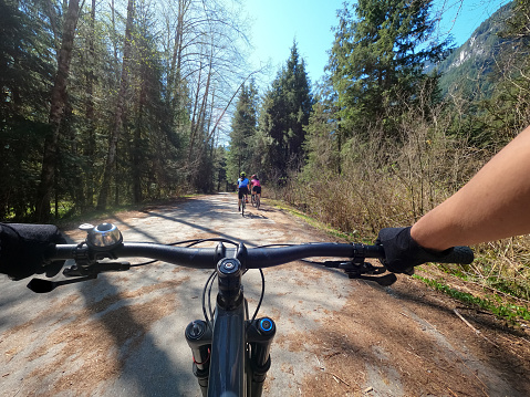 POV of father on mountain bike following daughters and wife on gravel and mountain bikes in North Vancouver, British Columbia, Canada