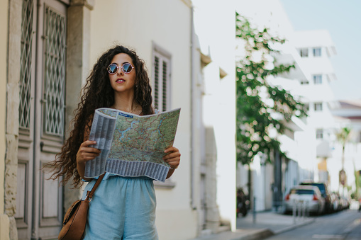Young hipster woman on summer holidays in Spain doing sightseeing and reading map in town