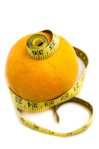 Diet concept: grapefruit and measuring tape on white background