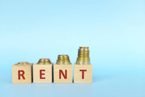 istock Rent increase concept. Word rent on wooden blocks in blue background with increasing stack of coins. 1315964705
