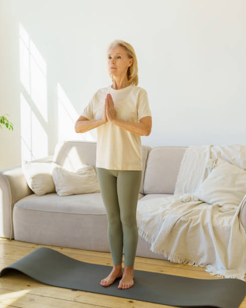 istock Peaceful mature woman meditating while practicing yoga on mat at home. 1315973153