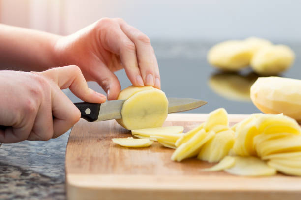 woman cutting up potatoes on a cutting board Cropped close up shot of a woman cutting up potatoes on a cutting board.Concept of preparing an traditional spanish omelette prepared potato stock pictures, royalty-free photos & images