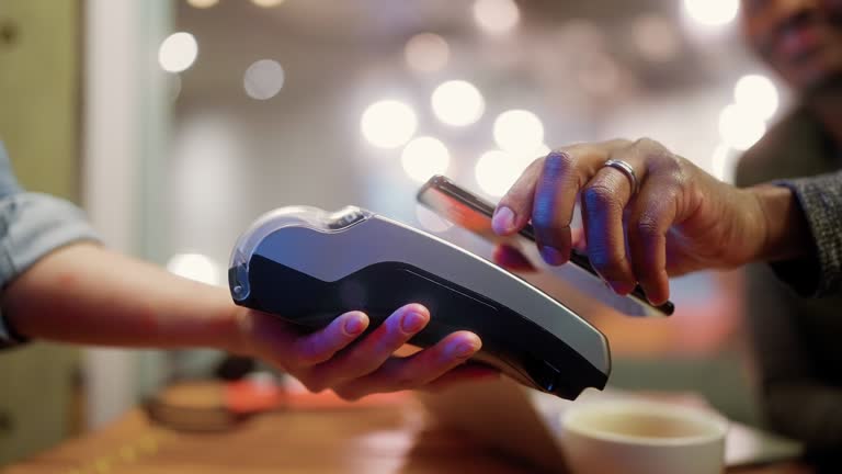 Man making contactless payment in cafe at night