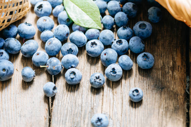 istock Freshly picked blueberries scattered on a rustic wooden table. Juicy and fresh blueberries with green leaves. The concept for healthy eating and nutrition. 1315981327