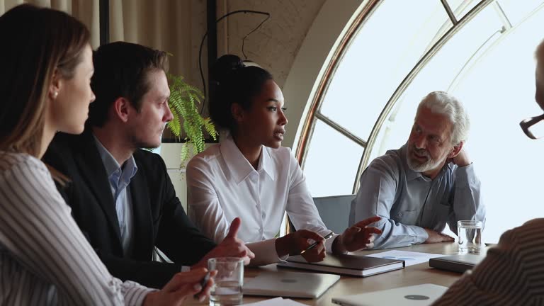 Confident african ethnicity leader holding negotiations meeting with diverse colleagues.