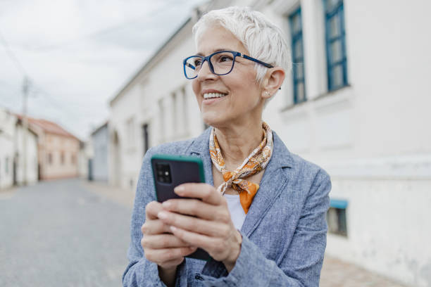 istock Senior woman is using mobile phone on the street 1315987978