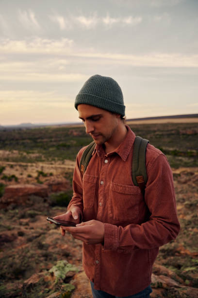 istock Handsome young man holding smartphone wearing cap and backpack o 1315990542