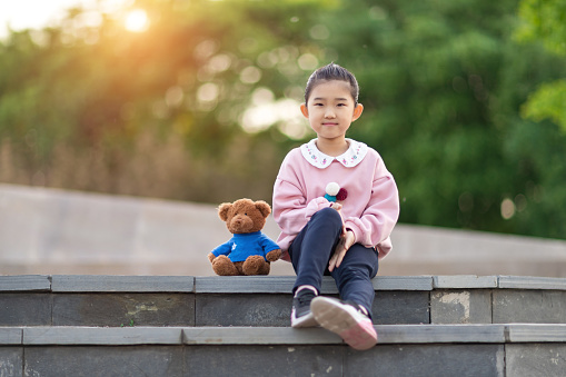 Cute Little Girl and Teddy Bear Sitting on Steps