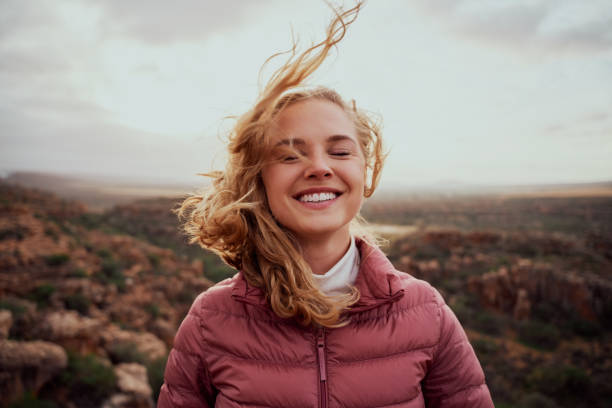 istock Smiling young confident woman with closed eyes feeling fresh wind against face standing on mountain hill 1315991420