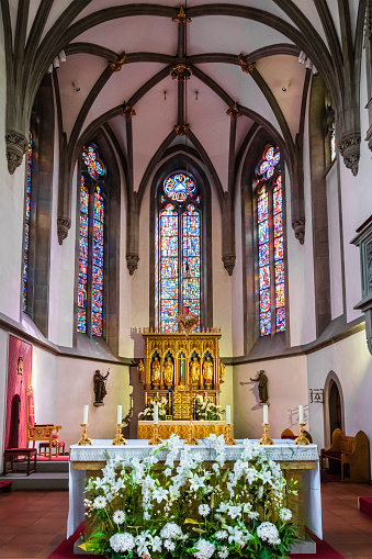 September 14, 2012: Part of All Saints' Church altar with beautiful flowers in a vase, two large white candles and a large wooden cross with Christ, shot in Wittenberg, Germany