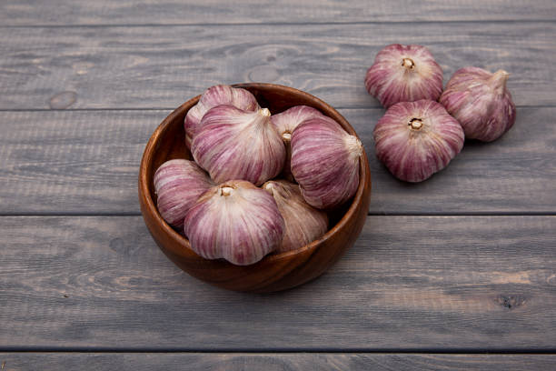istock Garlic bulbs in a wooden plate on a wooden table. Rustic style. 1315998818
